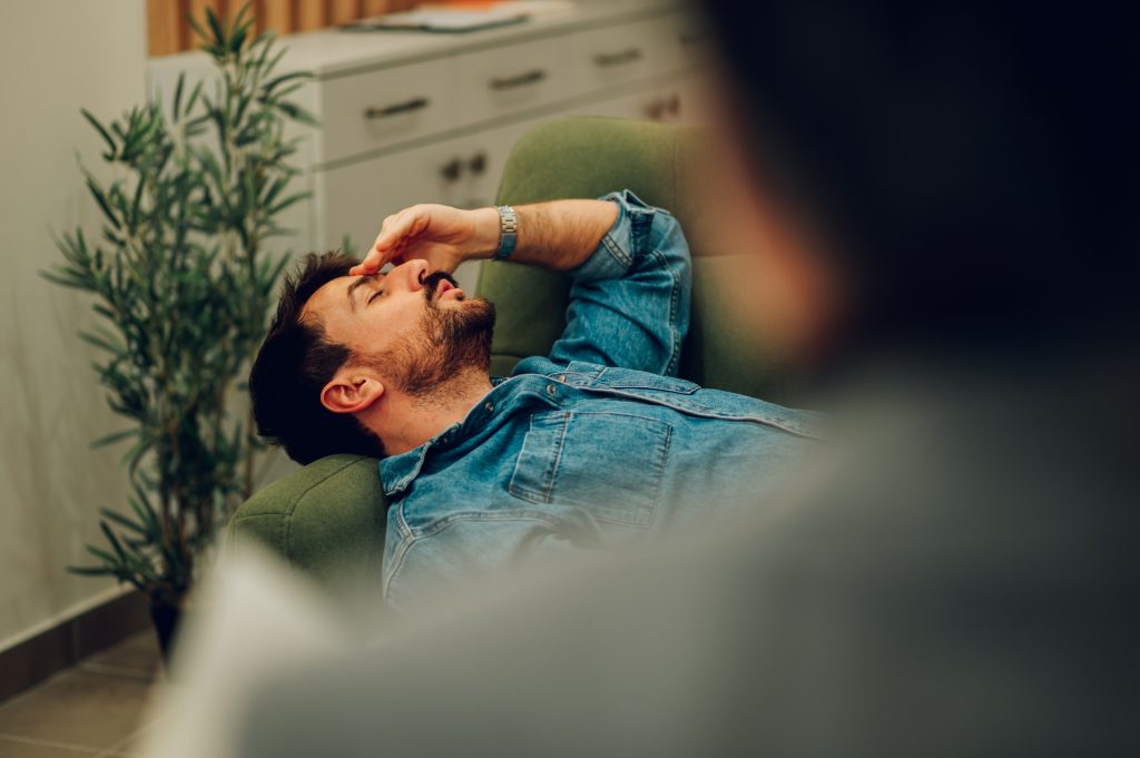 A depressed and anxious patient is lying down on a sofa in a psychotherapists office and discussing problems in life during the session - Etapes :