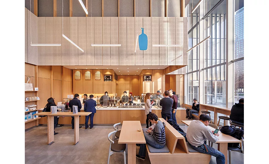 Busy modern cafe with a long wooden counter, barista station, and customers ordering and chatting.